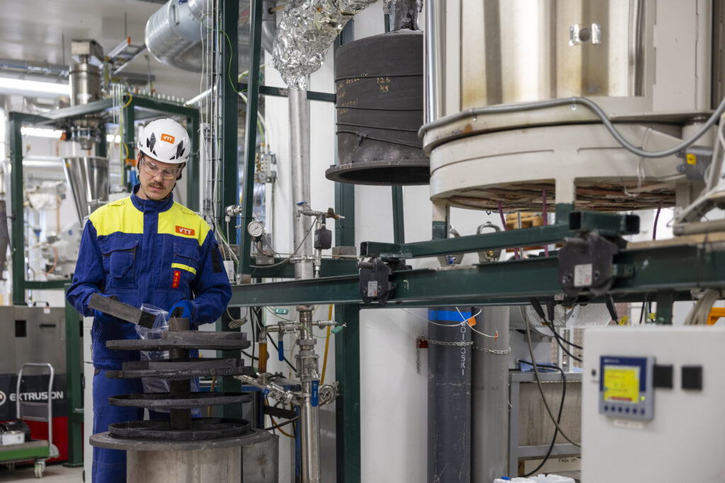 VTT researcher handling biochar in industrial environment.